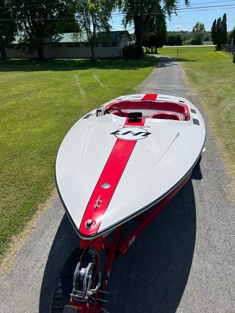 Slide: The Image of 1997 Four Winns U17 boat with red and gray design on a driveway. - 4