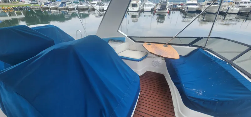 Slide: The Image of 1990 Carver 38 Santego yacht interior with blue covers and wooden table at marina. - 14