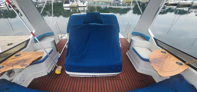 Slide: The Image of 1990 Carver 38 Santego yacht interior with blue seating and wooden tables at a marina. - 16