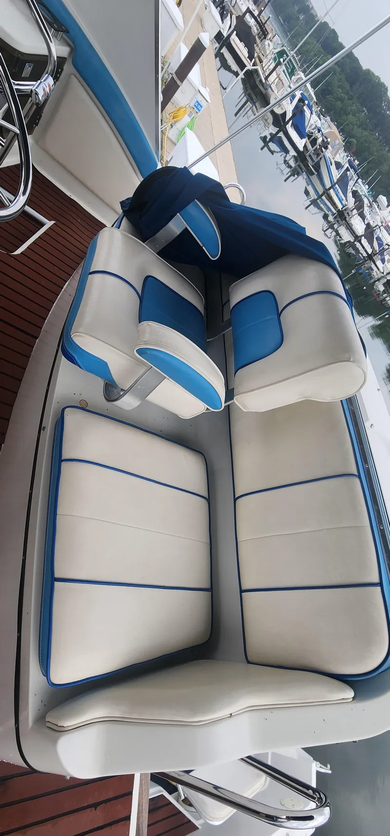 Slide: The Image of 1990 Carver 38 Santego boat interior with white and blue seating at a marina. - 18