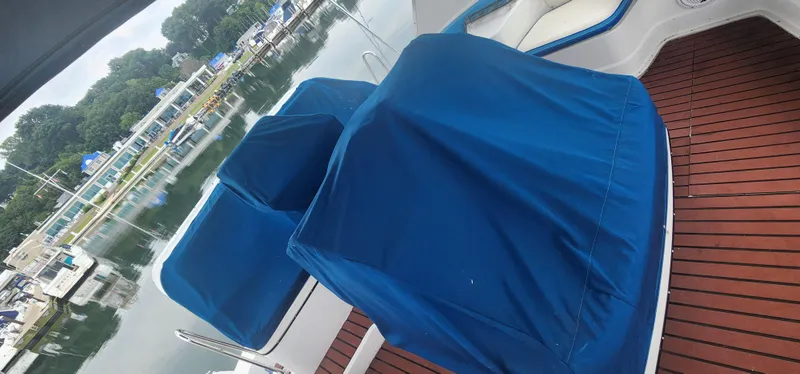 Slide: The Image of 1990 Carver 38 Santego yacht deck with blue-covered seating, docked at a marina. - 11