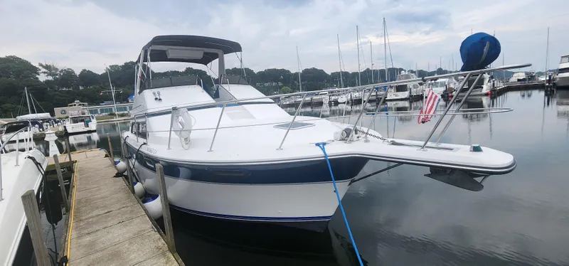 Slide: The Image of 1990 Carver 38 Santego yacht docked at a marina, surrounded by calm waters and other boats. - 3