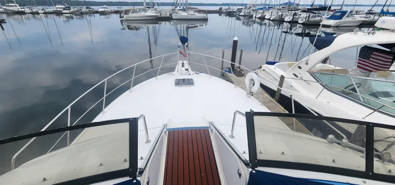 Slide: The Image of 1990 Carver 38 Santego yacht docked at a marina, surrounded by calm water and other boats. - 7