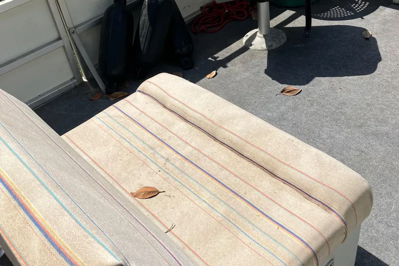 Slide: The Image of Interior of a 1996 Smoker Craft 820 boat with striped seating and fallen leaves. - 8