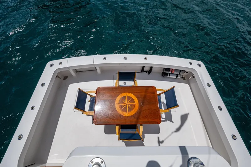 Slide: The Image of 2005 Viking 61 yacht deck with wooden table and chairs, overlooking ocean water. - 36