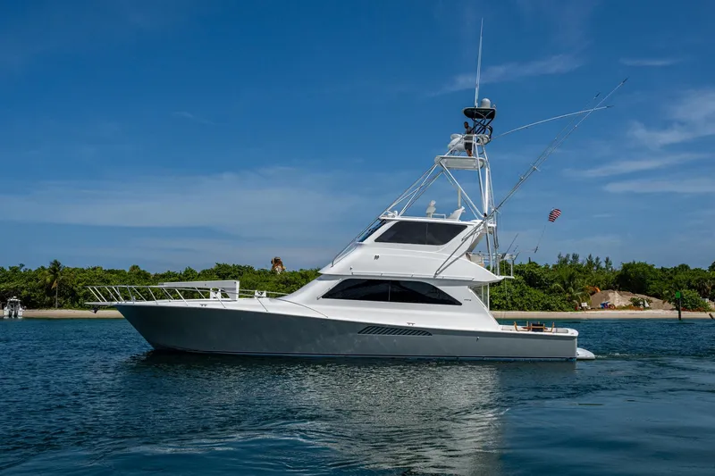 Slide: The Image of 2005 Viking 61 yacht cruising near a tropical shoreline under a clear blue sky. - 4