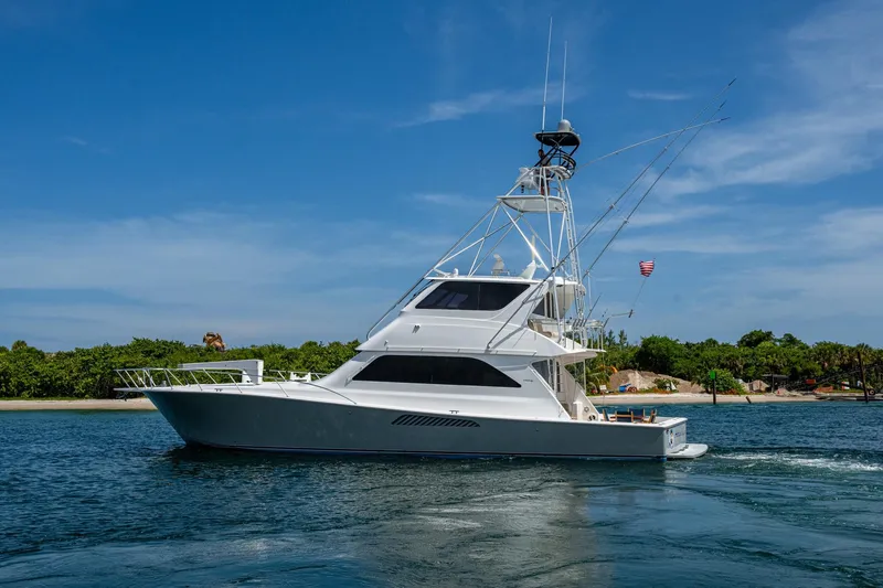 Slide: The Image of 2005 Viking 61 yacht cruising on a sunny day near a lush shoreline. - 5