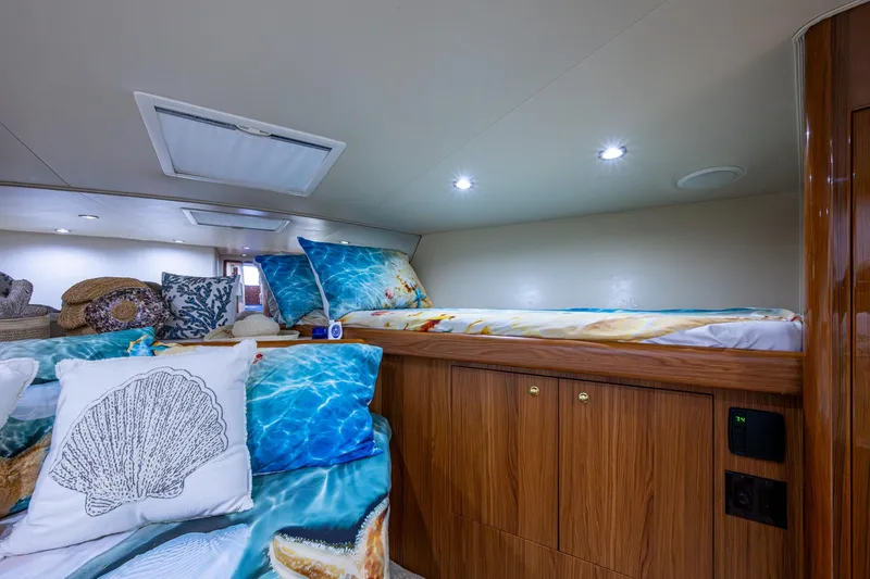 Slide: The Image of Cozy cabin interior of 2005 Viking 61 yacht with nautical-themed bedding and wooden cabinetry. - 82