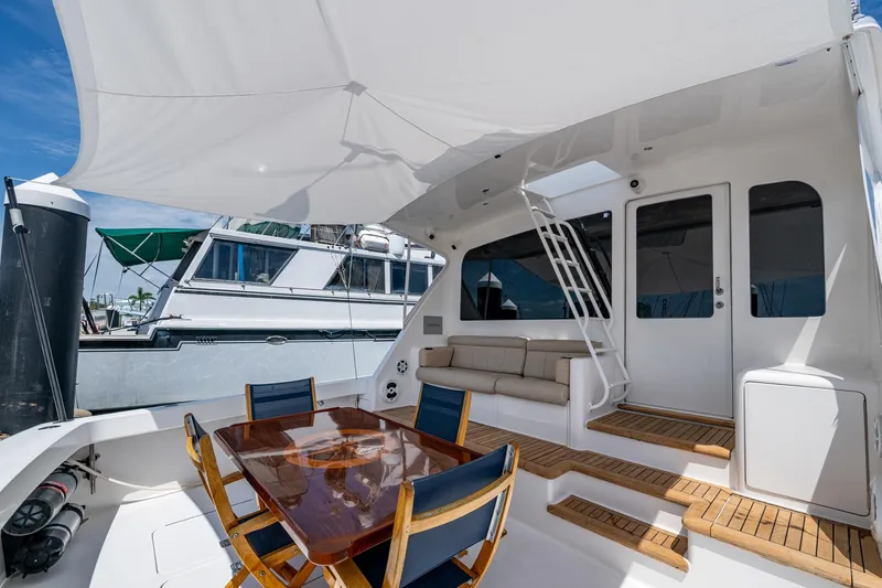 Slide: The Image of Luxurious 2005 Viking 61 yacht deck with seating, table, and canopy under clear skies. - 87