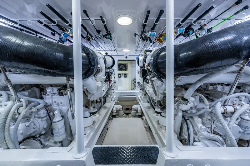 Slide: The Image of Engine room of a 2005 Viking 61 yacht, showcasing dual engines and fishing rods. - 98