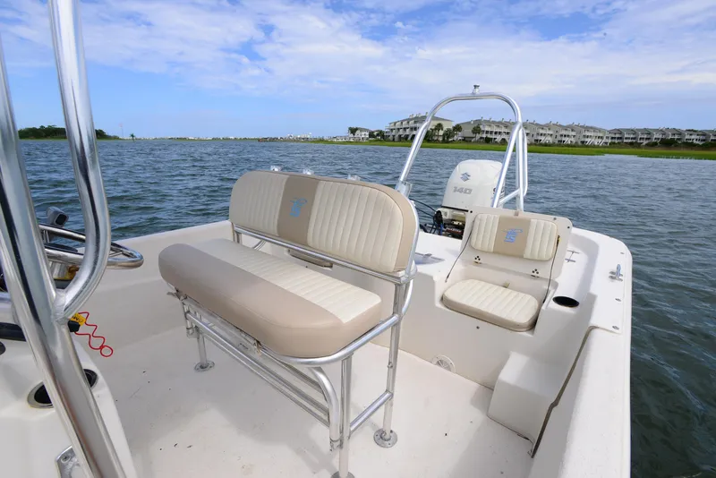 Slide: The Image of 2017 Carolina Skiff 218 DLV boat interior with seating, on calm water under blue sky. - 13