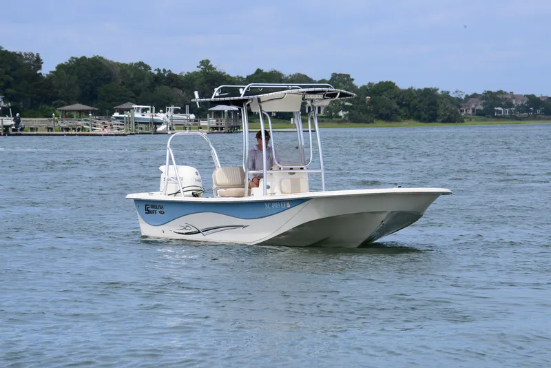 Slide: The Image of 2017 Carolina Skiff 218 DLV boat cruising on a calm lake with scenic background. - 2