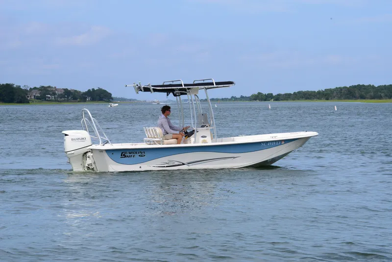 Slide: The Image of 2017 Carolina Skiff 218 DLV boat cruising on a calm lake with a Suzuki engine. - 9