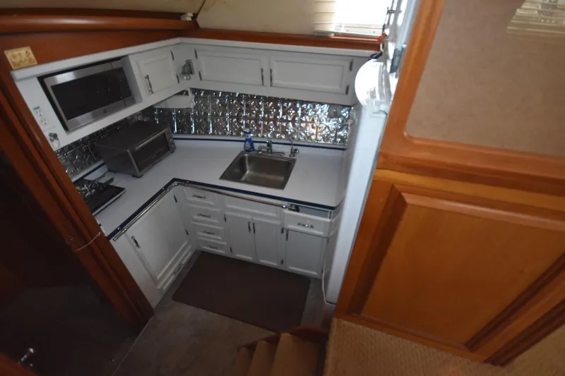 Slide: The Image of 1967 Hatteras 41 Twin Cabin kitchen with white cabinets and stainless steel appliances. - 26