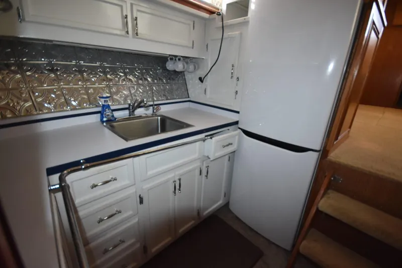 Slide: The Image of 1967 Hatteras 41 Twin Cabin kitchen with white cabinets and metallic backsplash. - 27