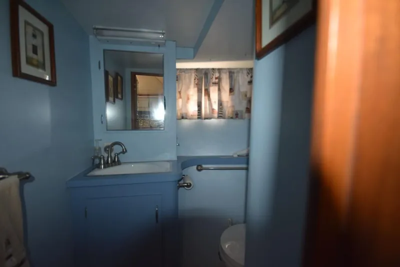 Slide: The Image of 1967 Hatteras 41 Twin Cabin bathroom with blue decor and nautical-themed curtains. - 30