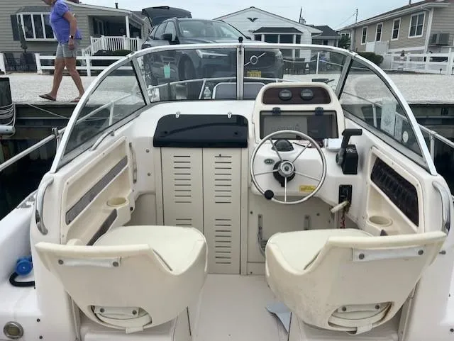 Slide: The Image of 2000 Grady-White Adventure 208 boat interior with steering wheel and dashboard, docked near houses. - 3