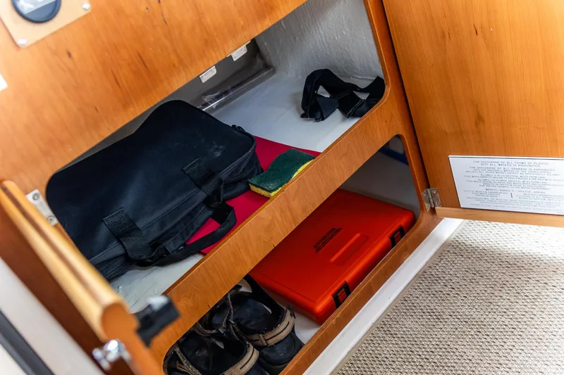 Slide: The Image of Storage compartment in 2023 Cutwater C-248 Coupe with bags, shoes, and safety equipment. - 16