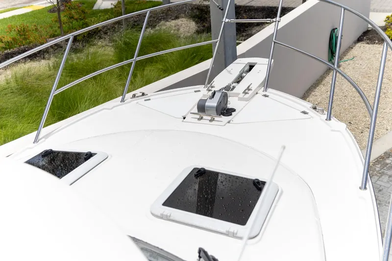 Slide: The Image of 2023 Cutwater C-248 Coupe boat deck with railing and hatches, docked near greenery. - 22