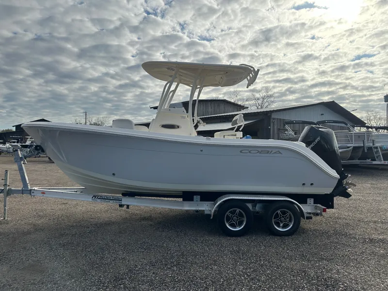 The Image of 2022 Cobia 220 Center Console boat on trailer under cloudy sky. - 0