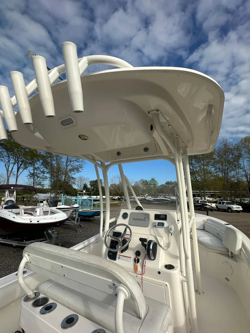 Slide: The Image of 2022 Cobia 220 Center Console boat with T-top, docked under a cloudy sky. - 10
