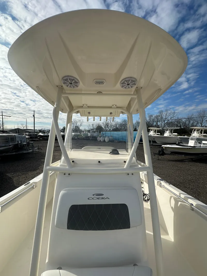 Slide: The Image of 2022 Cobia 220 Center Console boat with T-top, docked under a cloudy sky. - 14