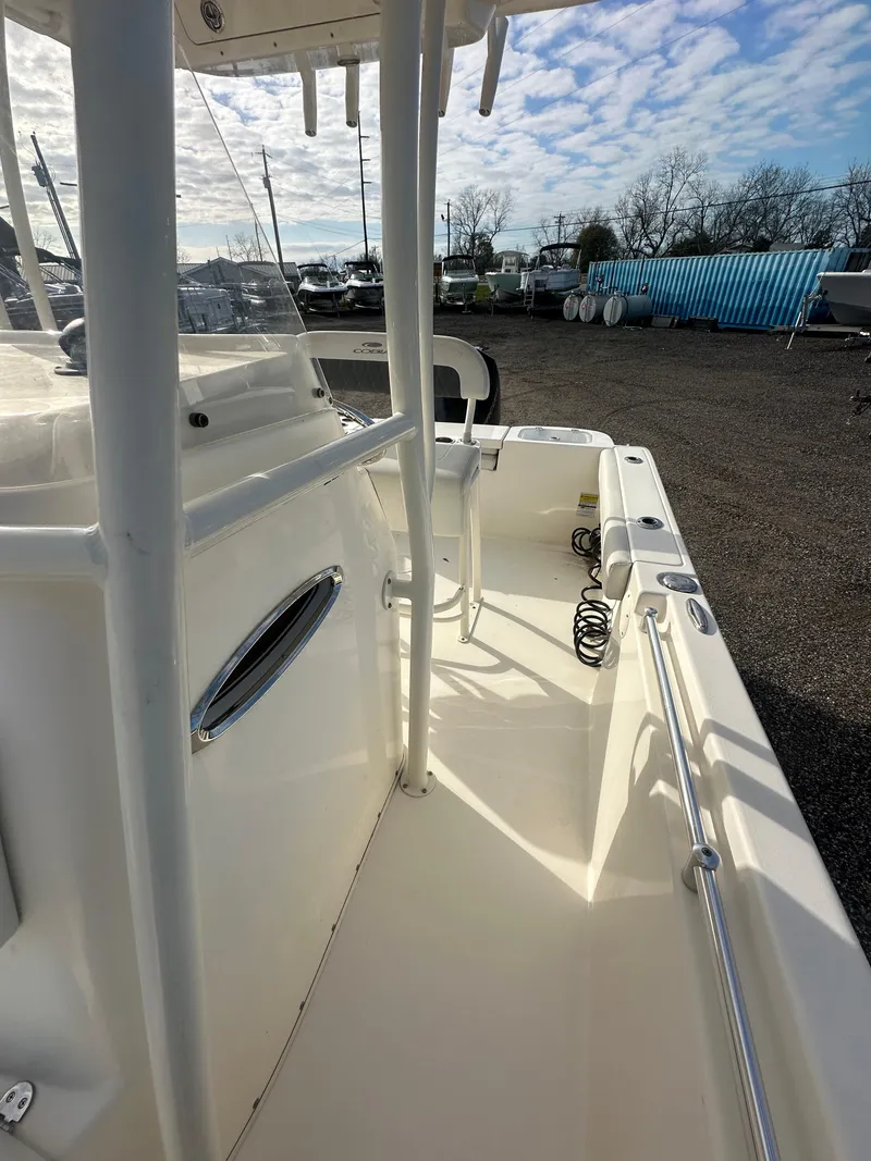 Slide: The Image of 2022 Cobia 220 Center Console boat, side view, docked under a partly cloudy sky. - 15