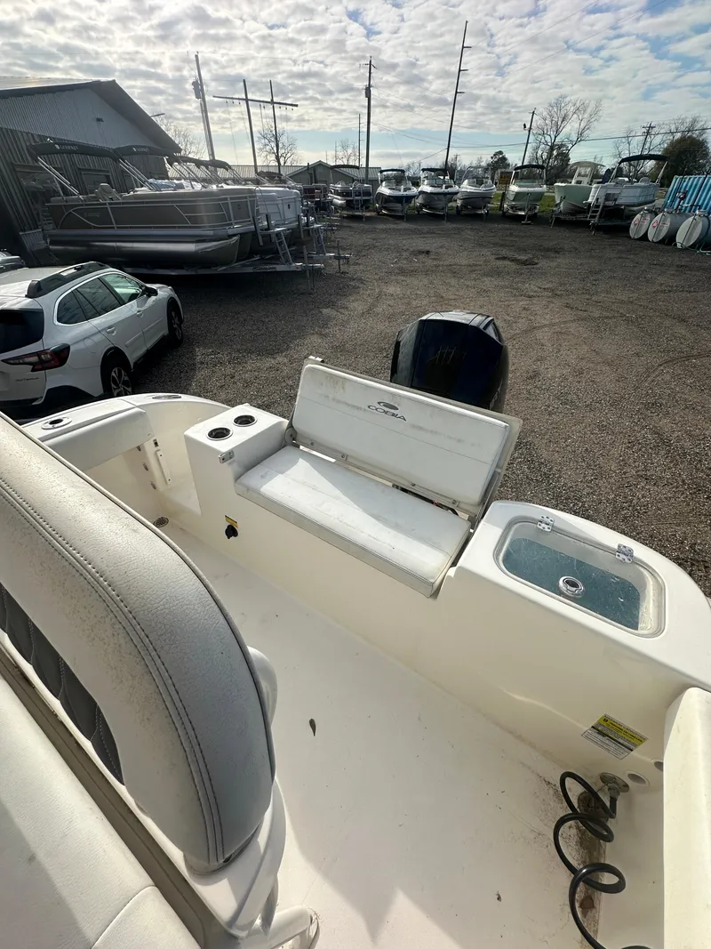 Slide: The Image of 2022 Cobia 220 Center Console boat in a marina with parked cars. - 18