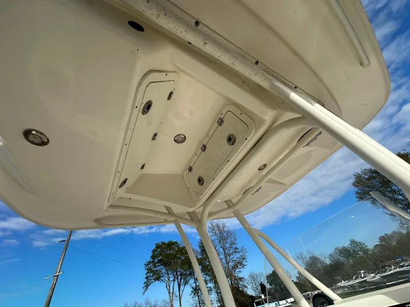 Slide: The Image of 2022 Cobia 220 Center Console boat, underside view with storage compartments and blue sky background. - 25