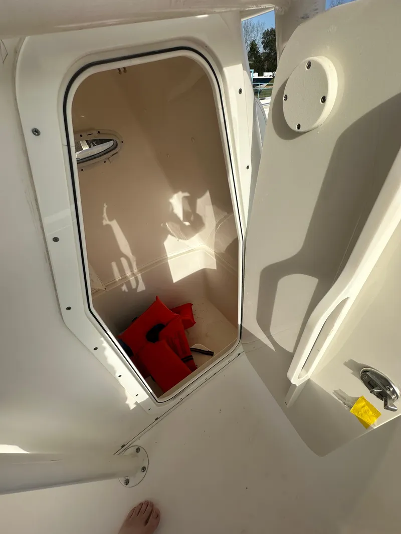 Slide: The Image of 2022 Cobia 220 Center Console boat storage compartment with life jacket. - 27