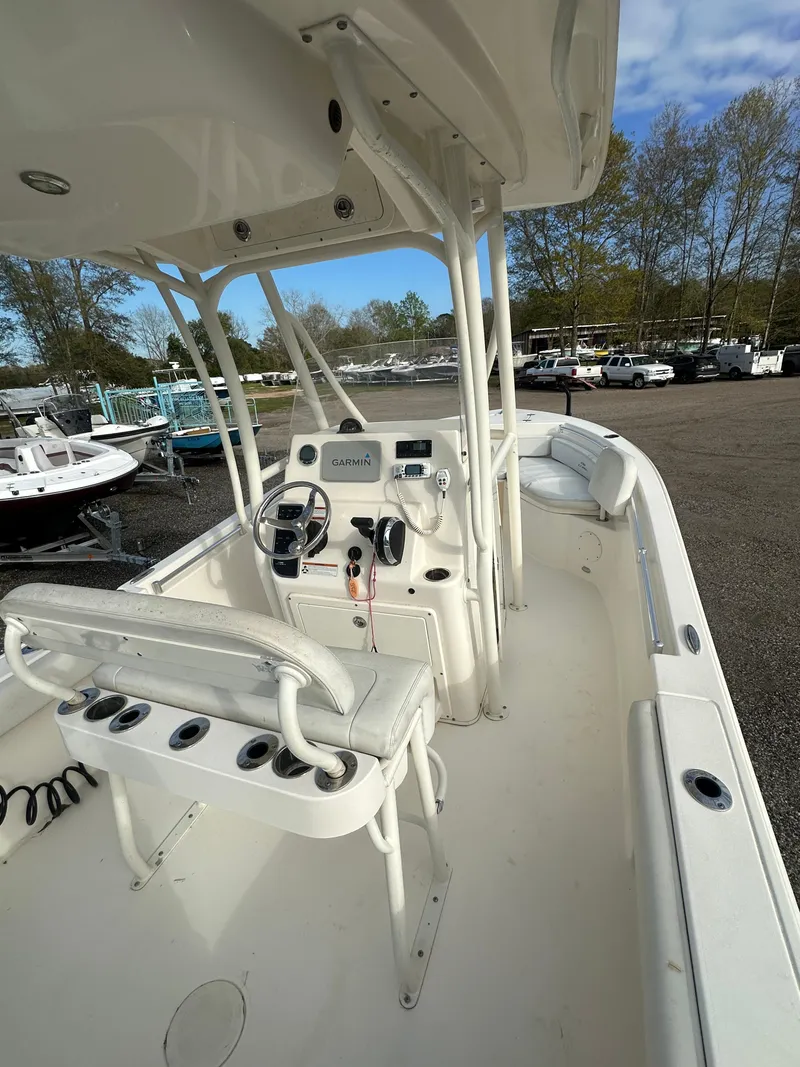 Slide: The Image of 2022 Cobia 220 Center Console boat with steering wheel and seating, parked outdoors. - 9