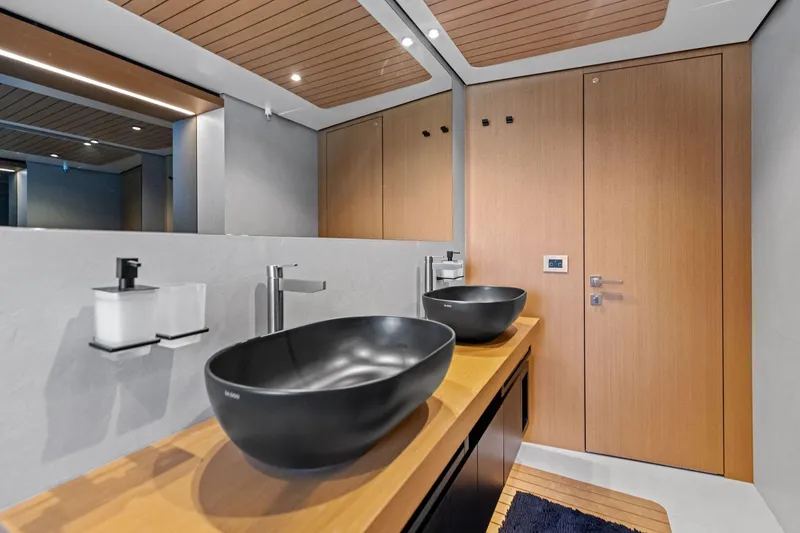 Slide: The Image of Modern bathroom interior on 2023 Wally WHY 150 yacht with sleek black sinks and wooden accents. - 101