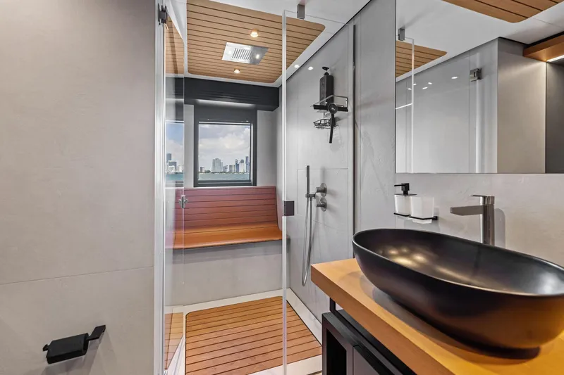 Slide: The Image of Modern yacht bathroom with sleek black sink, wooden accents, and city view. Wally WHY 150, 2023. - 97