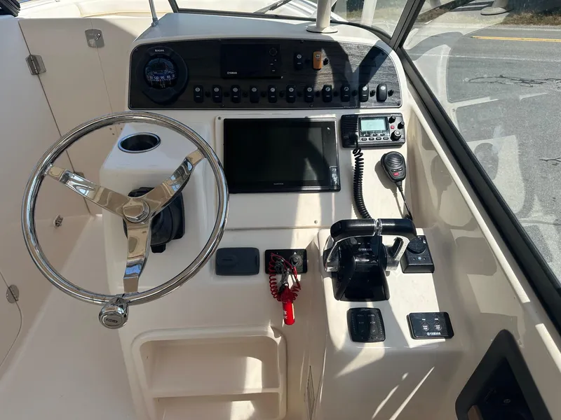 Slide: The Image of 2016 Grady-White Freedom 285 boat dashboard with steering wheel and control panel. - 2