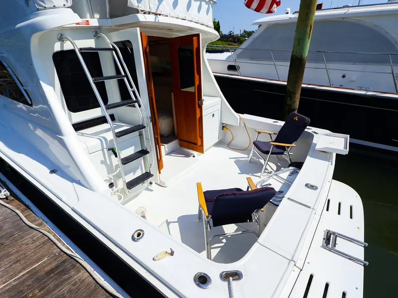 Slide: The Image of 1997 Luhrs 32 Convertible yacht with deck chairs and ladder, docked at marina. - 18
