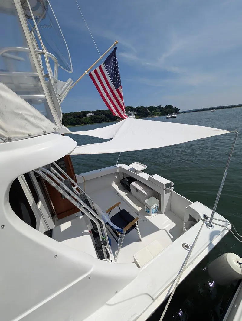 Slide: The Image of 1997 Luhrs 32 Convertible boat with American flag, docked on a sunny day. - 19