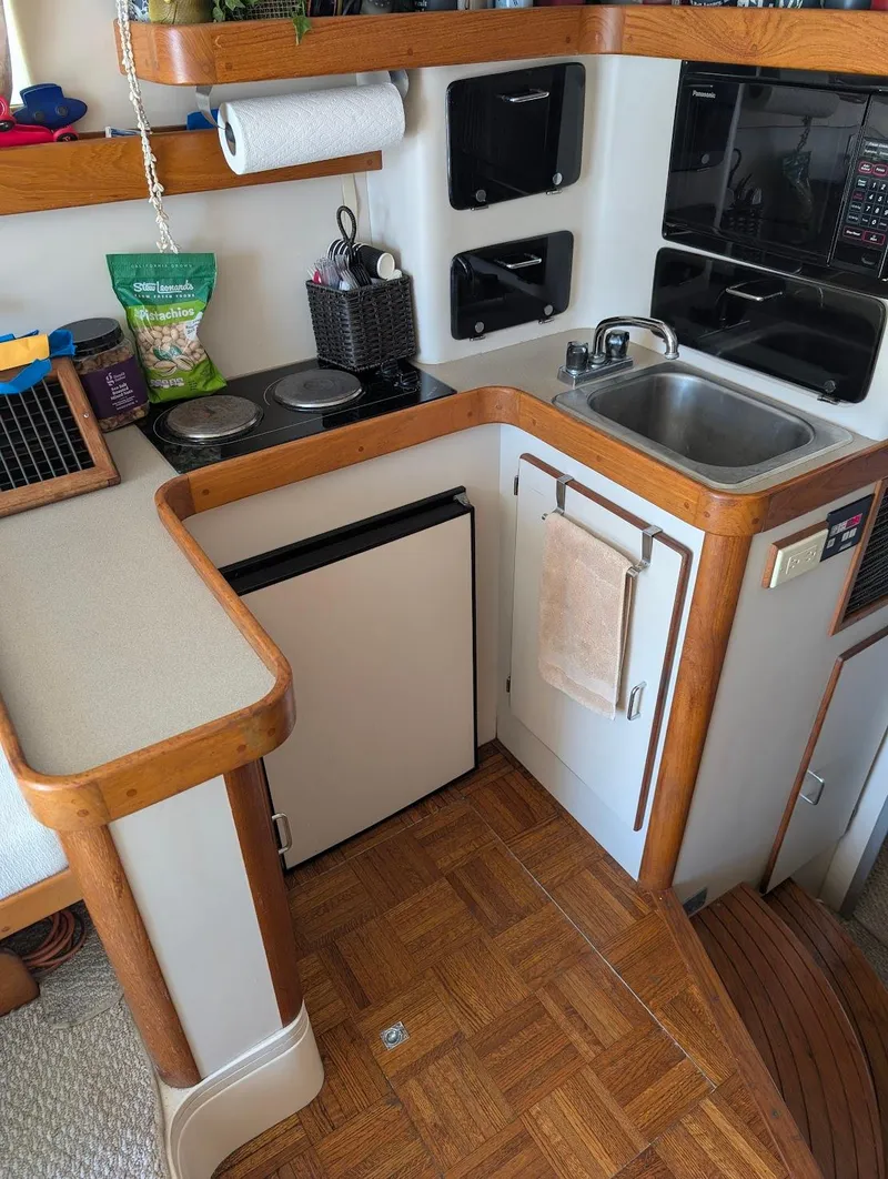 Slide: The Image of 1997 Luhrs 32 Convertible yacht kitchen with sink, stove, and compact fridge. - 25