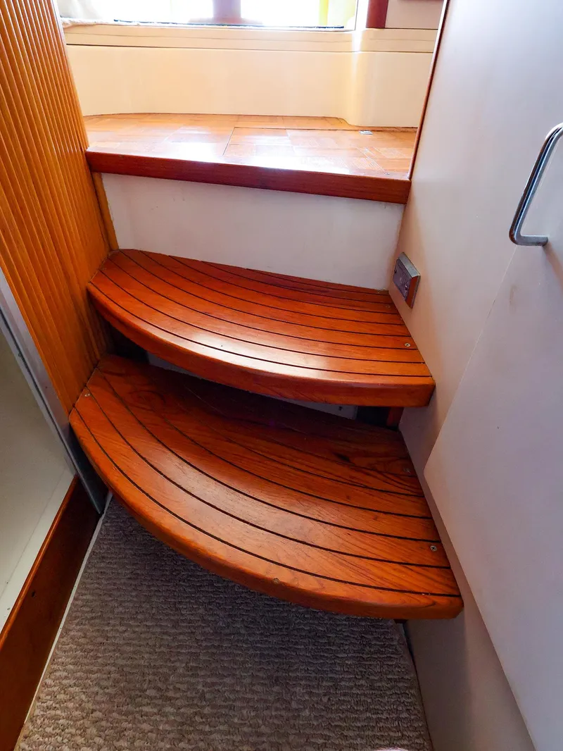 Slide: The Image of Wooden steps inside a 1997 Luhrs 32 Convertible boat, featuring curved design and carpeted flooring. - 29