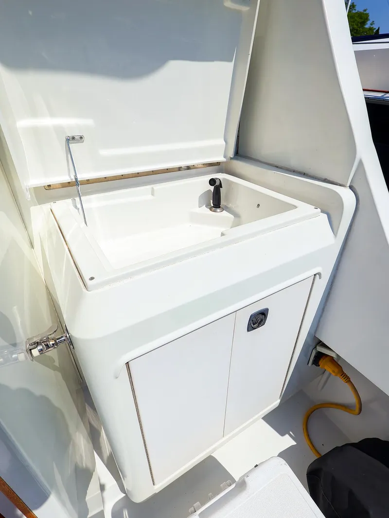Slide: The Image of 1997 Luhrs 32 Convertible boat sink with storage cabinet, open lid, and faucet. - 9