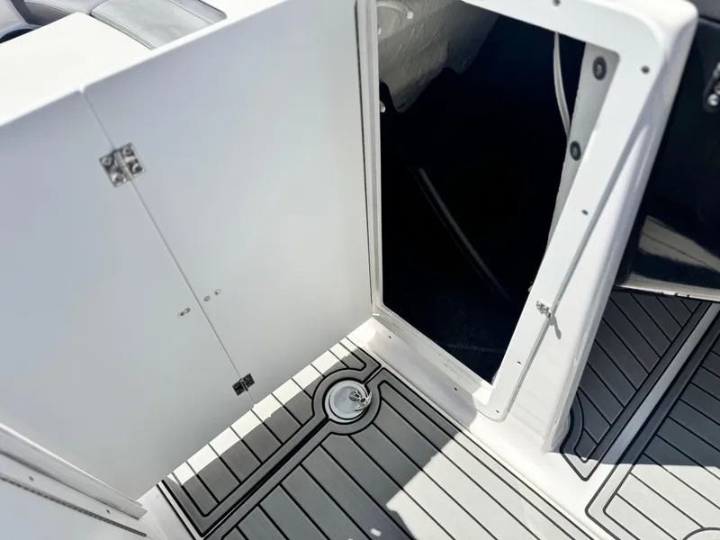 Slide: The Image of 2021 Yamaha SX210 boat storage compartment with open door and sleek flooring. - 25