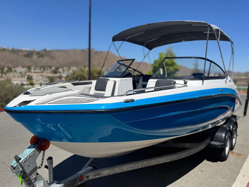 Slide: The Image of 2021 Yamaha Boats SX210 on trailer, blue and white, parked outdoors. - 3
