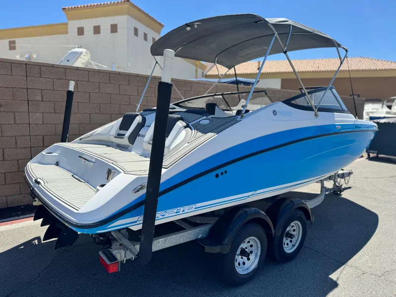 Slide: The Image of 2021 Yamaha Boats SX210 on trailer, blue and white, parked outdoors. - 5