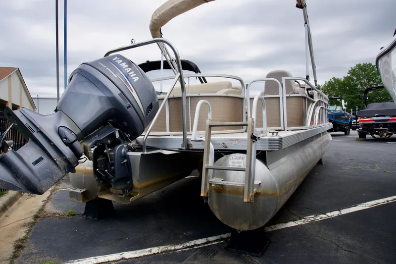 Slide: The Image of 2012 Bennington 24 SSL pontoon boat with Yamaha outboard motor, parked on pavement. - 2