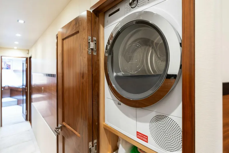 Slide: The Image of Laundry area inside 2023 Viking 80 Convertible yacht, featuring a modern dryer. - 26