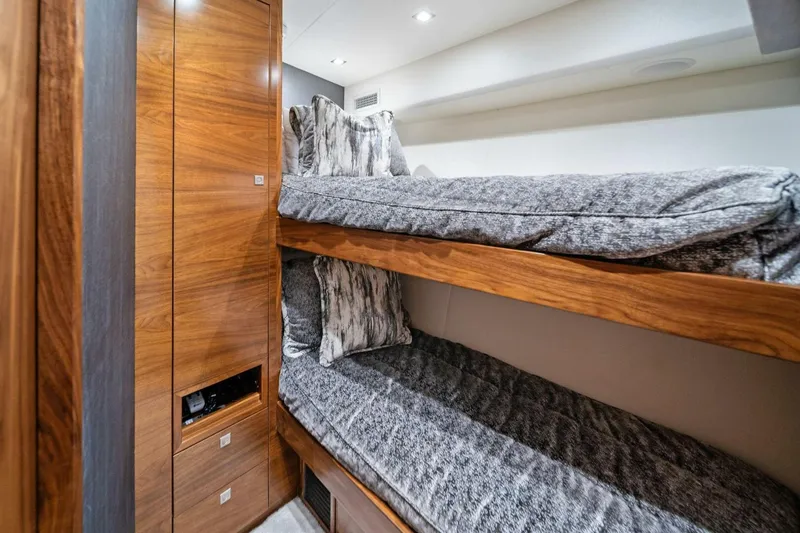 Slide: The Image of Bunk beds in 2023 Viking 80 Convertible yacht cabin with wooden accents and gray bedding. - 39