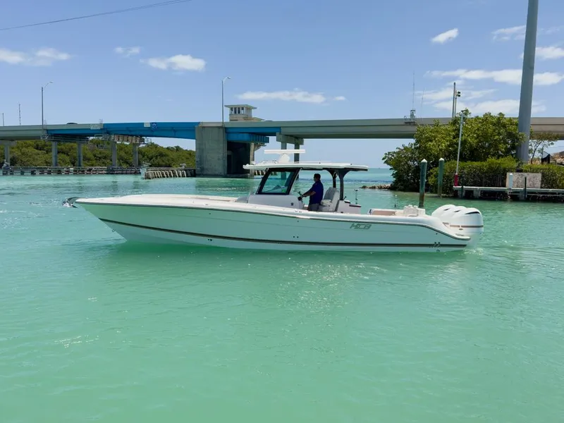 Slide: The Image of 2019 HCB 39 Speciale boat cruising on turquoise water near a bridge. - 2