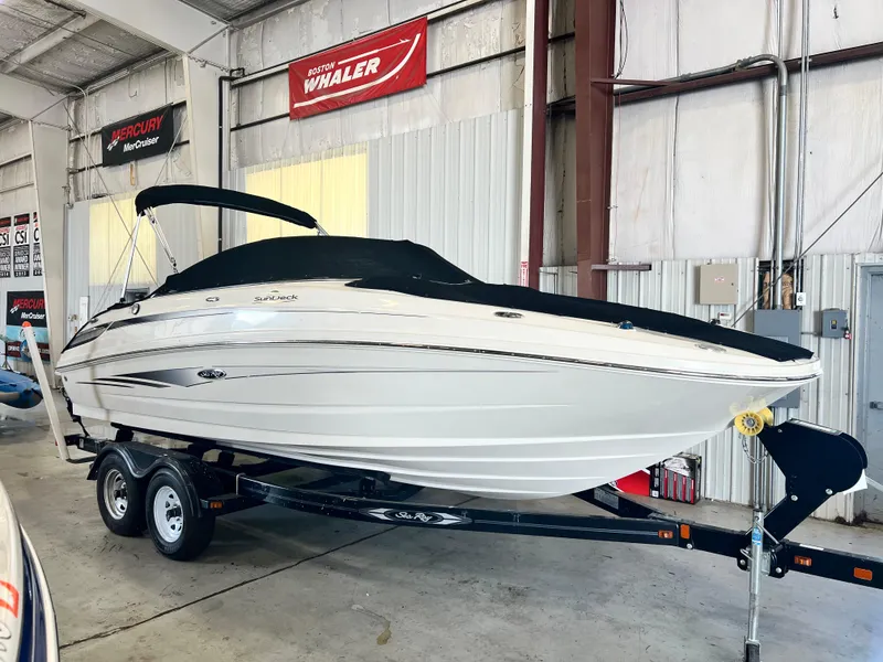 The Image of 2010 Sea Ray 220 Sundeck boat on trailer in indoor storage facility. - 1