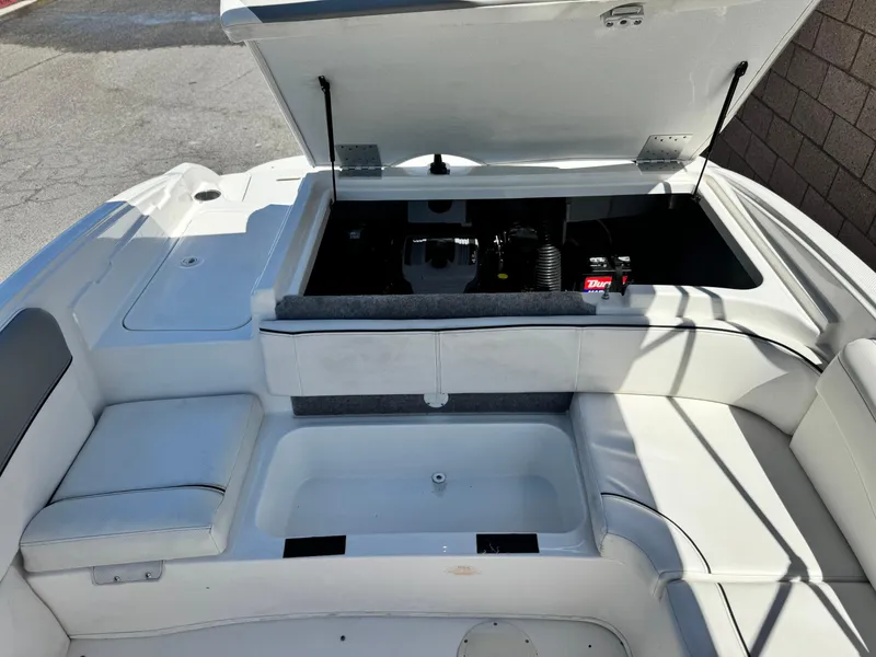 Slide: The Image of 2012 Bayliner 215 boat interior with open engine compartment and seating area. - 16