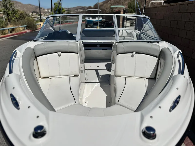 Slide: The Image of 2012 Bayliner 215 boat interior with white seating, docked outdoors. - 8
