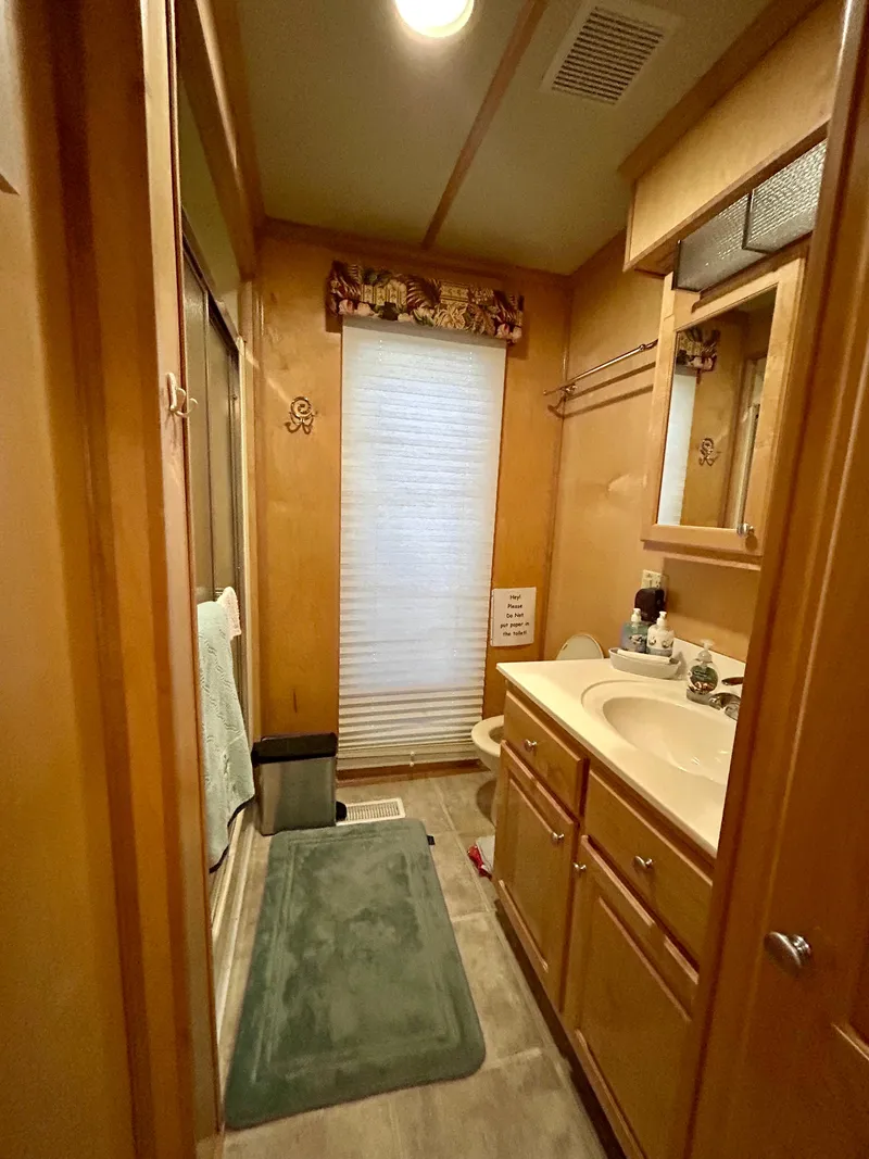 Slide: The Image of Compact bathroom in 2004 Horizon houseboat with wooden cabinets and green rug. - 12